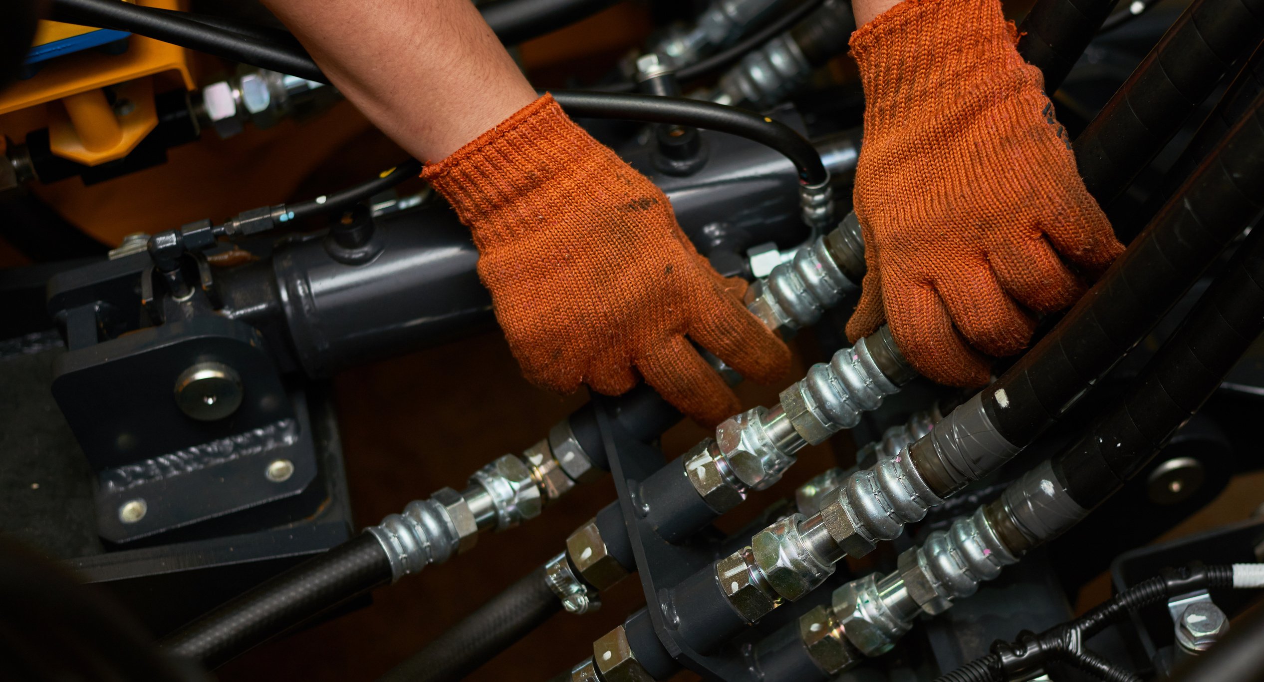 Low key photo of hydraulic pipes maintenance on heavy industry machine.